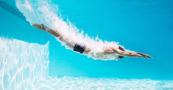 a man swimming underwater in a pool